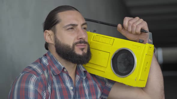 Close-up of Young Caucasian Man with Brown Eyes Listening To Music From Vintage Yellow Tape Recorder