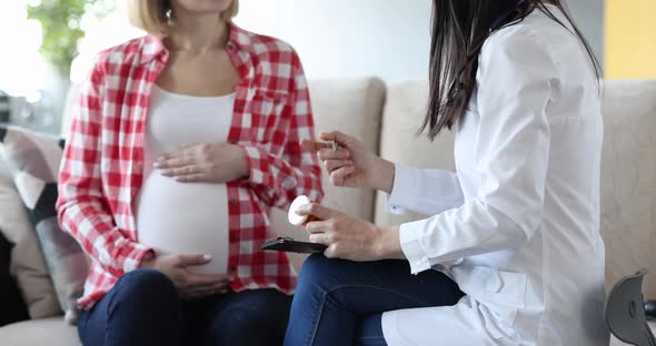 Therapist Gives Prescribed Medication to Pregnant Woman Sitting on Couch at Home
