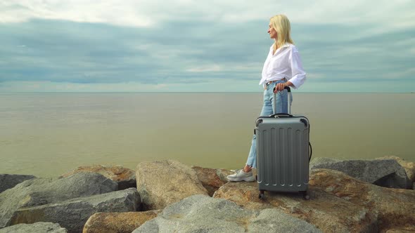 A beautiful woman with a suitcase on the background of the sea