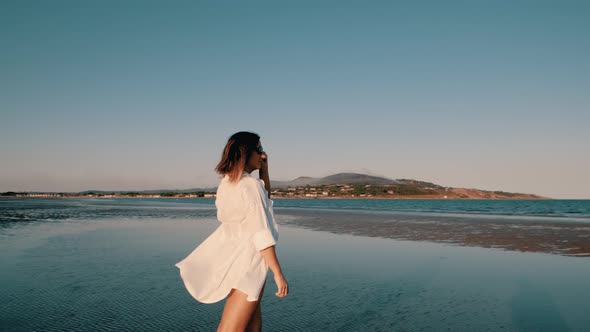 A woman walks barefoot on the beach