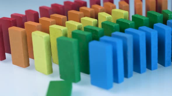 Line up of Dominoes in Rainbow Falling Colors with LGBT Colors of a Hand