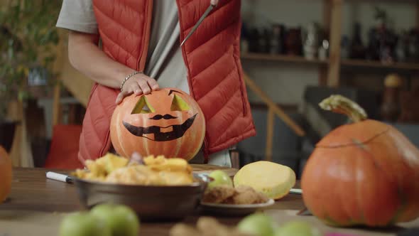 A Man Carves Brows of a Pumpkin Neatly