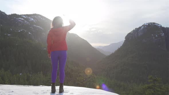 Adventurous Girl Hiking in the Mountains During a Sunny Winter Sunset