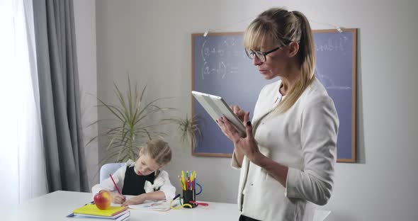 Portrait of Adult Caucasian Woman Standing with Tablet As Little Pretty Schoolgirl Writing