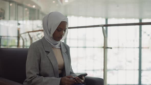 AfricanAmerican Business Woman in Hijab Texts on Phone