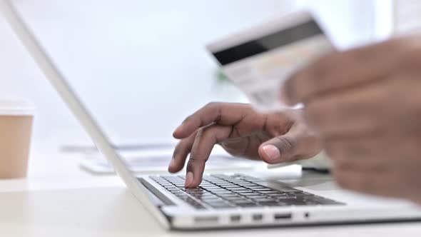 Close Up of Hands of African Man Making Online Payment on Laptop