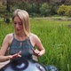 Popular Modern Hang Musical Instrument in the Hands of a Beautiful Blonde in Park - VideoHive Item for Sale