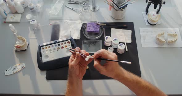 Closeup of Painting a Ceramic Dental Crown with a Thin Brush By Hand