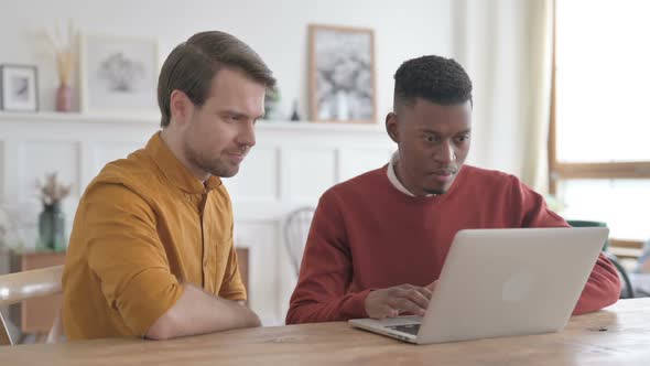 African Man and Young Man Celebrating Success on Laptop