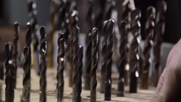 Close-up of a Worker's Hand Choosing Drills for Work. The Concept of Production and Construction