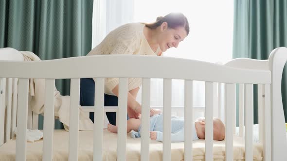 Little Baby Boy Lying in Cradle and Looking at His Smiling Mother