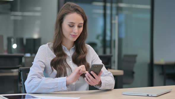 Attractive Young Businesswoman using Smartphone at Work