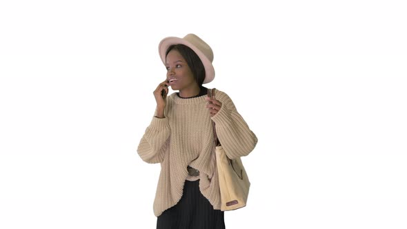 Frustrated African American Woman in Knitted Sweater and White Hat Talking on Her Phone on White
