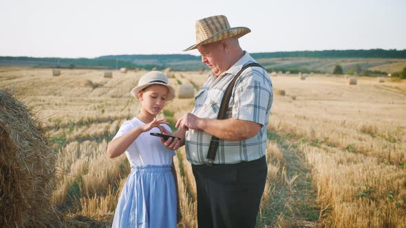 Little Girl with Grandfather in Field Haystacks, Grandfather Farmer Is Teaching the Younger