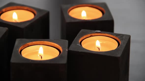 A set of black stone block candle holders with lit tealight candles on a livingroom stone table.