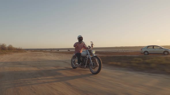 Motorcyclist Driving His Motorbike on the Dirt Road During Sunset  Shot