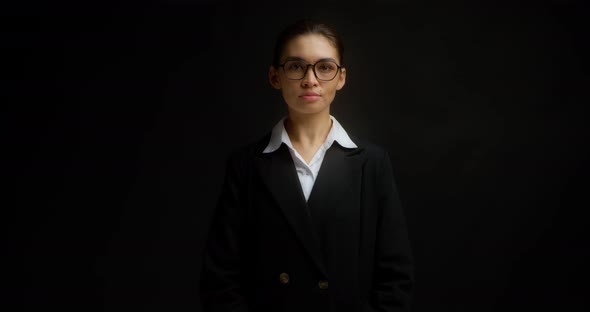 Asian Business Woman in Glasses and Formal Clothes Smiles and Looks at Camera