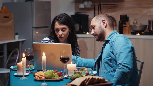 Couple Using Laptop During Dinner