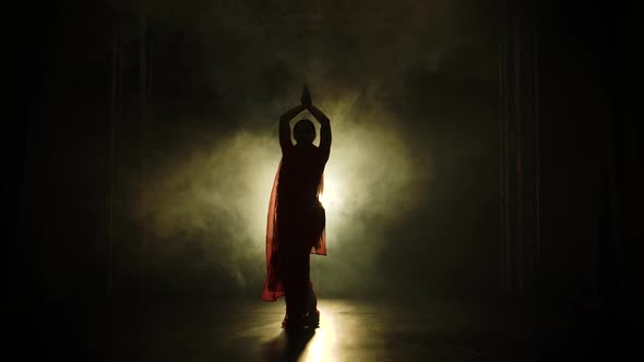 Silhouette a Young Girl Dancer in a Red Sari. Indian Folk Dance. Shot in a Dark Studio with Smoke