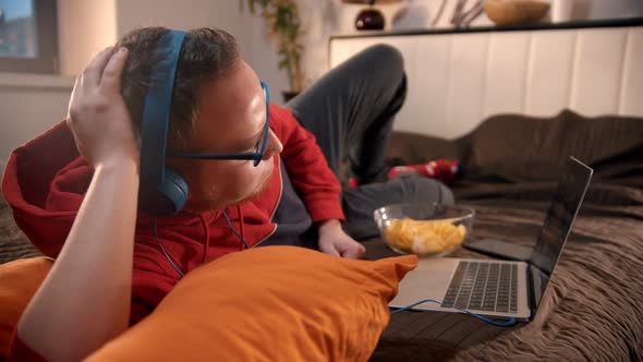 Young Man in Headphones Lying on the Bed and and Watching Movie