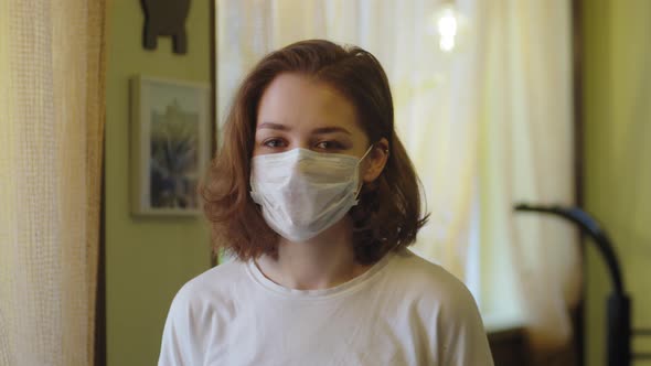 Young Student Teenager Girl in Protective Mask Standing Near Window on Home Self Isolation