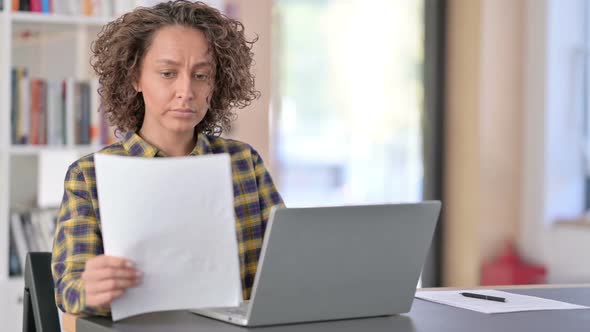 Mixed Race Woman with Documents Working on Laptop