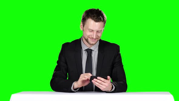 Businessman Sitting at the Table and Uses Phone, Green Screen