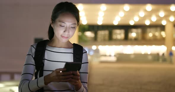 Woman looking at mobile phone in city at night