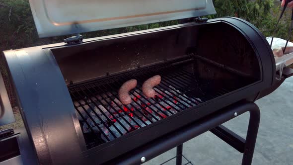 Putting Sausages on the grill to cook them on the BBQ.