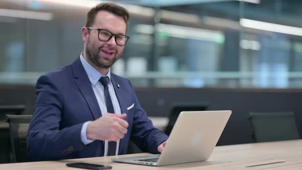 Middle Aged Businessman Using Laptop with Thumbs Up Sign
