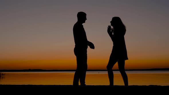 Silhouettes Of Men And Women Quarrel At Sunset On The Seashore