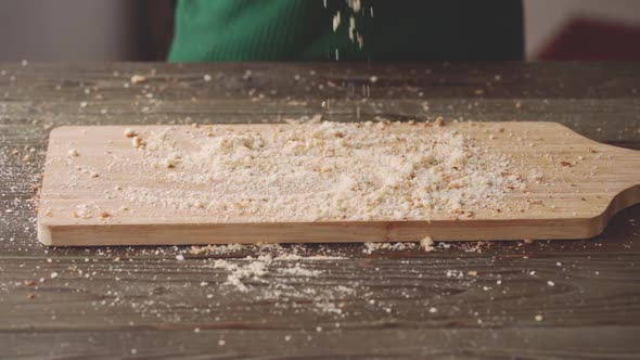 Female Hand Drops Bread Crumbs on Wooden Board