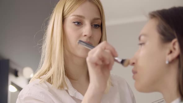 Closeup of a MUA Using Pink Sponge for Putting on a Cosmetic Product