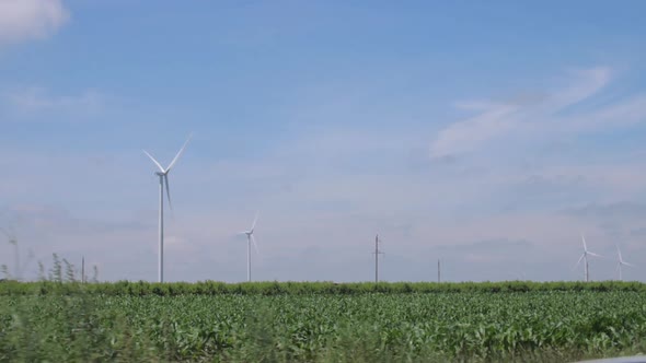 Wind Turbines Generate Clean Energy in Green Field in Spring