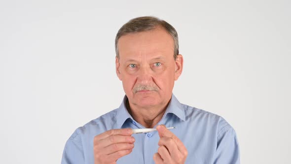 elderly man measures the temperature with a thermometer