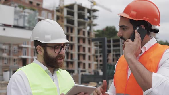 Engineer Speaks on Mobile Phone on Construction Site and Checks the Work of the Worker. Builder