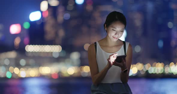 Woman checking on mobile phone in city at night