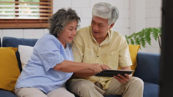 Asian senior couple using tablet searching online shopping.