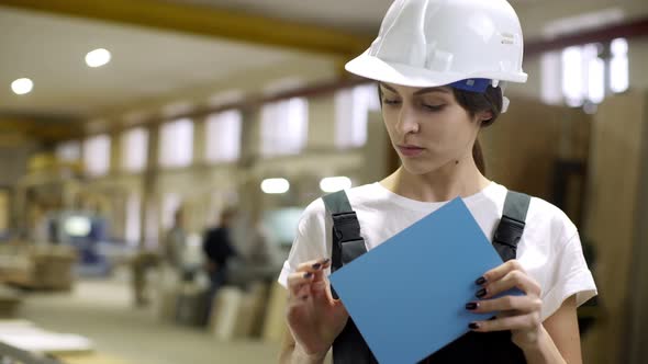 Portrait of Attractive Caucasian Woman in Helmet Holding and Supervising Furniture Detail While