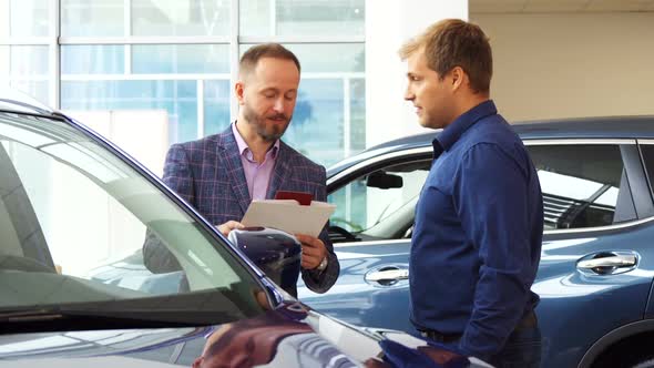 The Seller in the Suit Shows the Customer the Car Interior