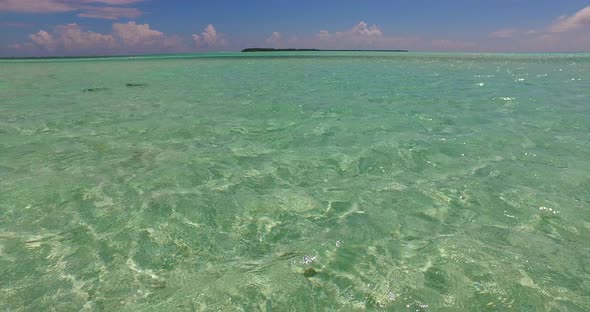 Tropical fly over tourism shot of a sunshine white sandy paradise beach and aqua blue ocean backgrou