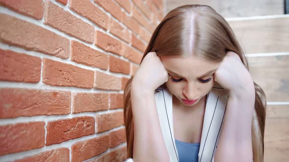 Worried Upset Young Woman Holding Head By Hand Having Hurt and Loss Feeling Medium Closeup