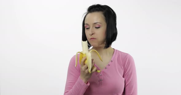 Young Beautiful Woman Eating Big, Fresh Banana on White Background