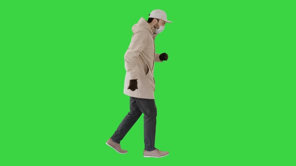 Young Man in Outdoor Clothes and Medical Mask Jogging on a Green Screen, Chroma Key