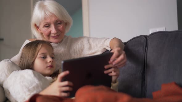 Grandmother stroking girl on head and watching something