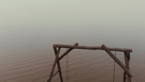 Empty Decorative Wooden Swings Stand in Tranquil Sea Water