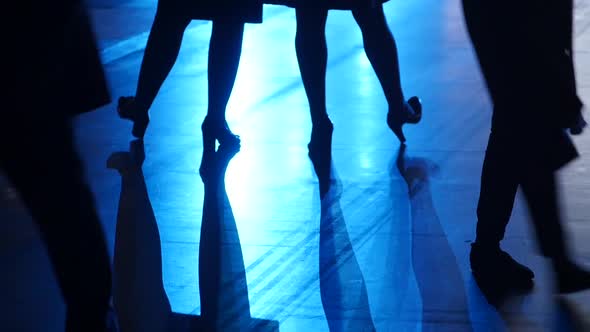 Two Pair of Female Slender Legs in Blue Backlight Background