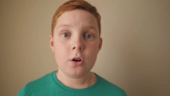 Little Redhaired Boy Looking Into Camera with Wow Expression Indoor