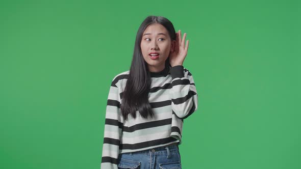 Asian Listening To Something Carefully While Standing In Front Of Green Screen Background