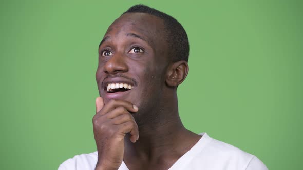 Young Happy African Man Thinking Against Green Background